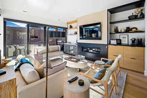 Living area with light wood-style flooring, a glass covered fireplace, recessed lighting, and built in shelves