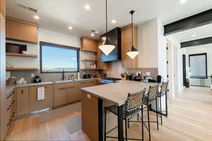 Kitchen featuring decorative light fixtures, a kitchen bar, open shelves, light countertops, and tasteful backsplash