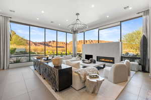 Living area featuring a mountain view, expansive windows, light tile patterned floors, a glass covered fireplace, and recessed lighting