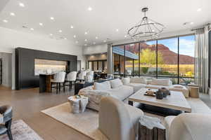 Living room with a mountain view, recessed lighting, floor to ceiling windows, light tile patterned floors, and a chandelier