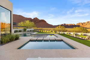 View of pool with a mountain view, an in-ground hot tub, and a patio