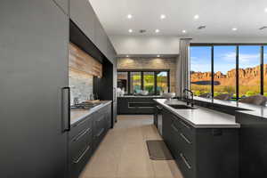 Kitchen featuring modern cabinets, dark cabinets, recessed lighting, light tile patterned flooring, and tasteful backsplash