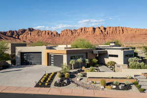 Contemporary home featuring driveway, a garage, a mountain view, stucco siding, and a chimney