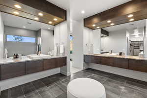 Full bathroom featuring recessed lighting, two vanities, dark tile patterned floors, and a spacious closet