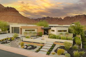 Rear view of property with an attached garage, concrete driveway, a mountain view, and stucco siding