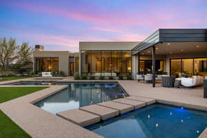 Pool at dusk with an outdoor hangout area, an outdoor pool, a patio area, and an in-ground hot tub