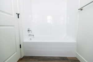 Bathroom with shower / bathtub combination and dark wood finished floors