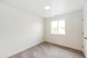 Empty room featuring light carpet and baseboards