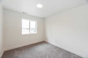 Carpeted spare room featuring baseboards