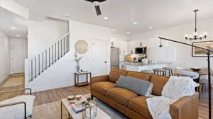 Living area featuring light wood-type flooring, a chandelier, and ceiling fan