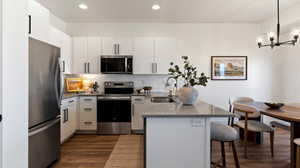 Kitchen featuring a peninsula, stainless steel appliances, white cabinetry, and a breakfast bar