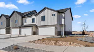 Modern inspired farmhouse with brick siding, an attached garage, board and batten siding, and concrete driveway
