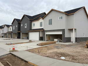 View of front of property featuring brick siding, a garage, board and batten siding, and a residential view