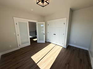 Unfurnished bedroom featuring a closet and dark wood-style flooring