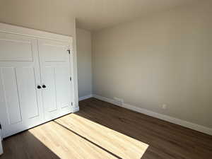 Unfurnished bedroom with a closet and dark wood finished floors