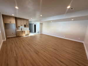 Unfurnished living room with recessed lighting, light wood-type flooring, and stairs