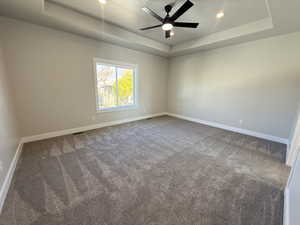 Unfurnished room featuring a raised ceiling, carpet flooring, recessed lighting, and a ceiling fan