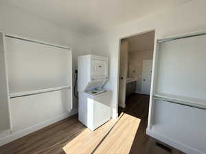 Washroom featuring dark wood-style floors and estacked washer and dryer