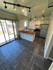Kitchen with track lighting, crown molding, a textured ceiling, backsplash, and freestanding refrigerator