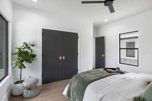 2nd Bedroom on main floor featuring wood floors, ceiling fan, a large closet, and large windows alowing lots of natural lighting.