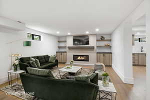 Basement Living area with real wood-flooring, a tile fireplace, shelving and extra storage.