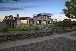 View of the front of home featuring stone exterior, a 2nf floor pation, a chimney, and modern themed design.