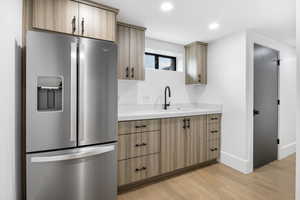 Kitchenette with stainless steel fridge with ice dispenser, light hard wood floors, and quartz countertops.