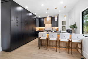 Kitchen featuring dark cabinets, decorative light fixtures, and a large breakfast bar.