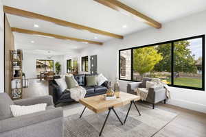 Living room on main floor with large windows, wood beams, and a gas firplace.