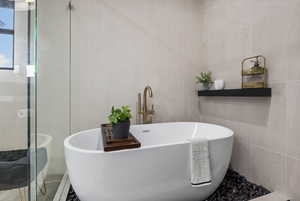 Master bath with a soaker tub, tile walls, and a dual head shower.
