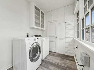 Laundry room with dark wood finished floors, orginal cabinets and drawers, and high end front load washer and dryer