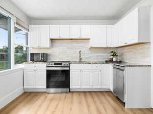 Kitchen featuring granite counters, stainless steel appliances, and white cabinets
