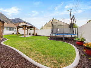 Fenced backyard with a trampoline, a gazebo, and a patio