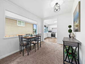 Dining space with light colored carpet and crown molding
