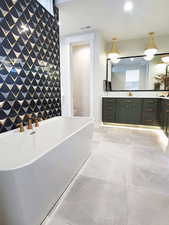 Bathroom with vanity, a freestanding tub, recessed lighting, light tile patterned flooring, and an accent wall