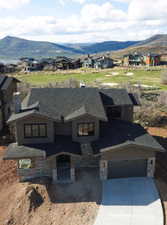 View of front of property featuring a mountain view, driveway, and stone siding