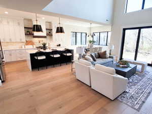 Living area featuring light wood-style floors, recessed lighting, and a high ceiling