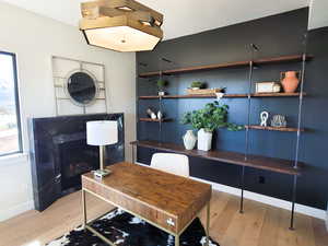 Home office featuring light wood-type flooring and a glass covered fireplace