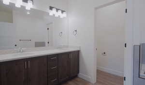 Full bath with double vanity and light wood finished floors