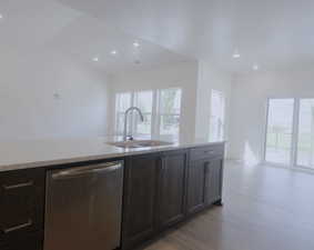 Kitchen featuring stainless steel dishwasher, plenty of natural light, light stone countertops, light wood-type flooring, and recessed lighting
