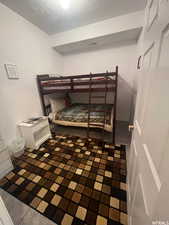 Bedroom with a textured ceiling and a textured wall