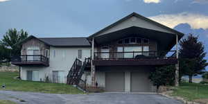 View of front of property with a front lawn, stone siding, stairway, a garage, and asphalt driveway