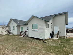 Back of house featuring entry steps, a yard, and a shingled roof
