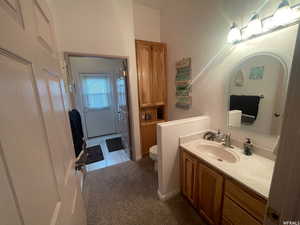 Half bathroom with vanity, dark tile patterned floors, and a textured wall
