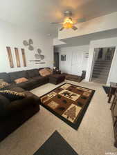 Living room featuring a textured ceiling, carpet floors, stairway, and a ceiling fan