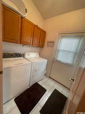Washroom featuring light tile patterned floors, cabinet space, and washing machine and clothes dryer