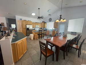Dining area with high vaulted ceiling, a chandelier, light tile patterned flooring, ceiling fan, and recessed lighting