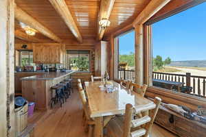 Dining space featuring light wood-style floors, healthy amount of natural light, and a wooden ceiling with exposed beams