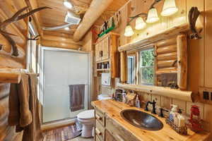 Full bathroom with a stall shower, rustic walls, vanity, wood ceiling, and light wood-style flooring