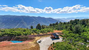 View of mountain backdrop featuring a forest and a nearby body of water